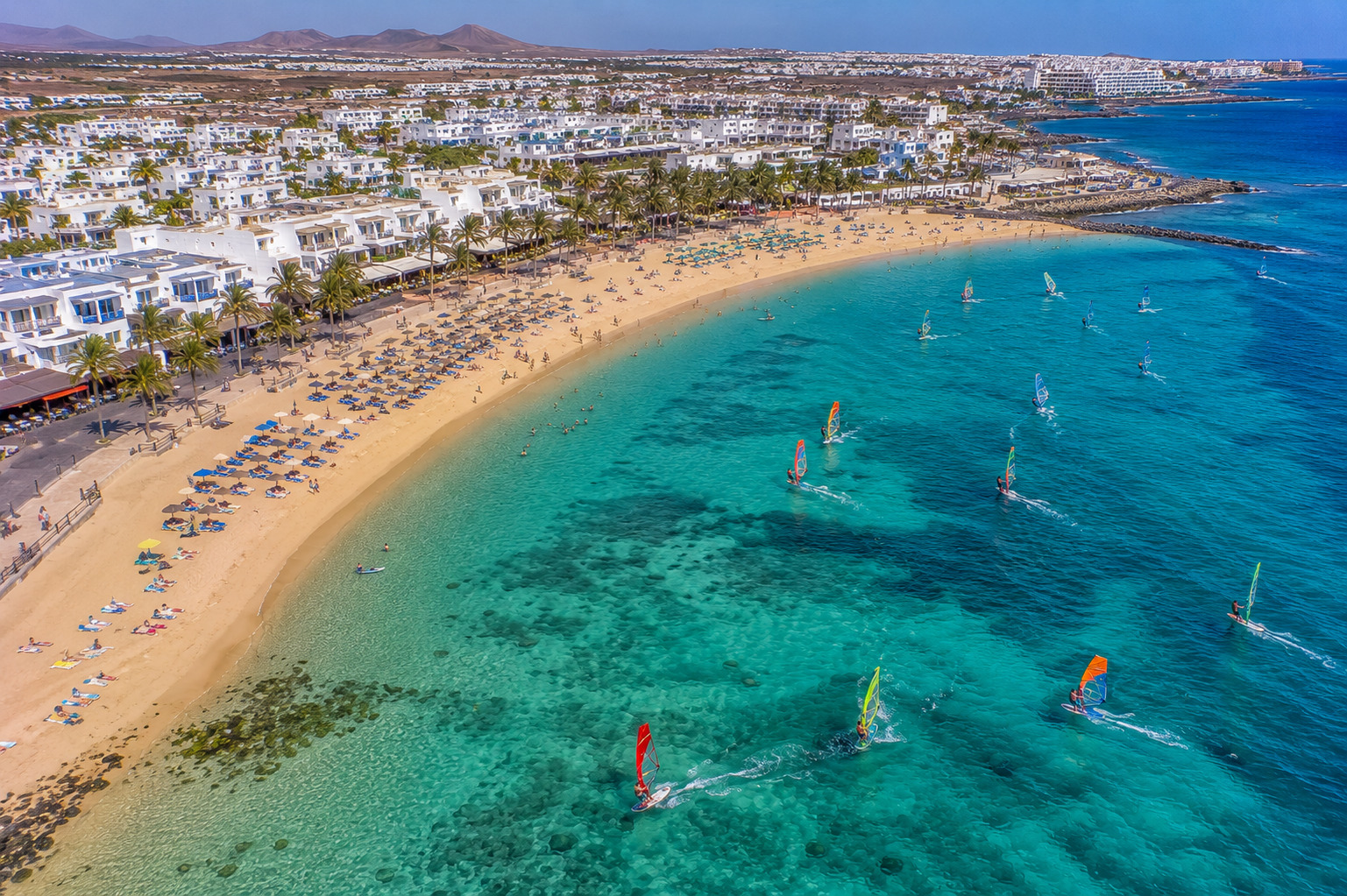 Puerto del Carmen på Lanzarote – helikoptervy över Kanarieöarnas största resort med 7 km strandremsa, vitkalkade hotell och Atlanten