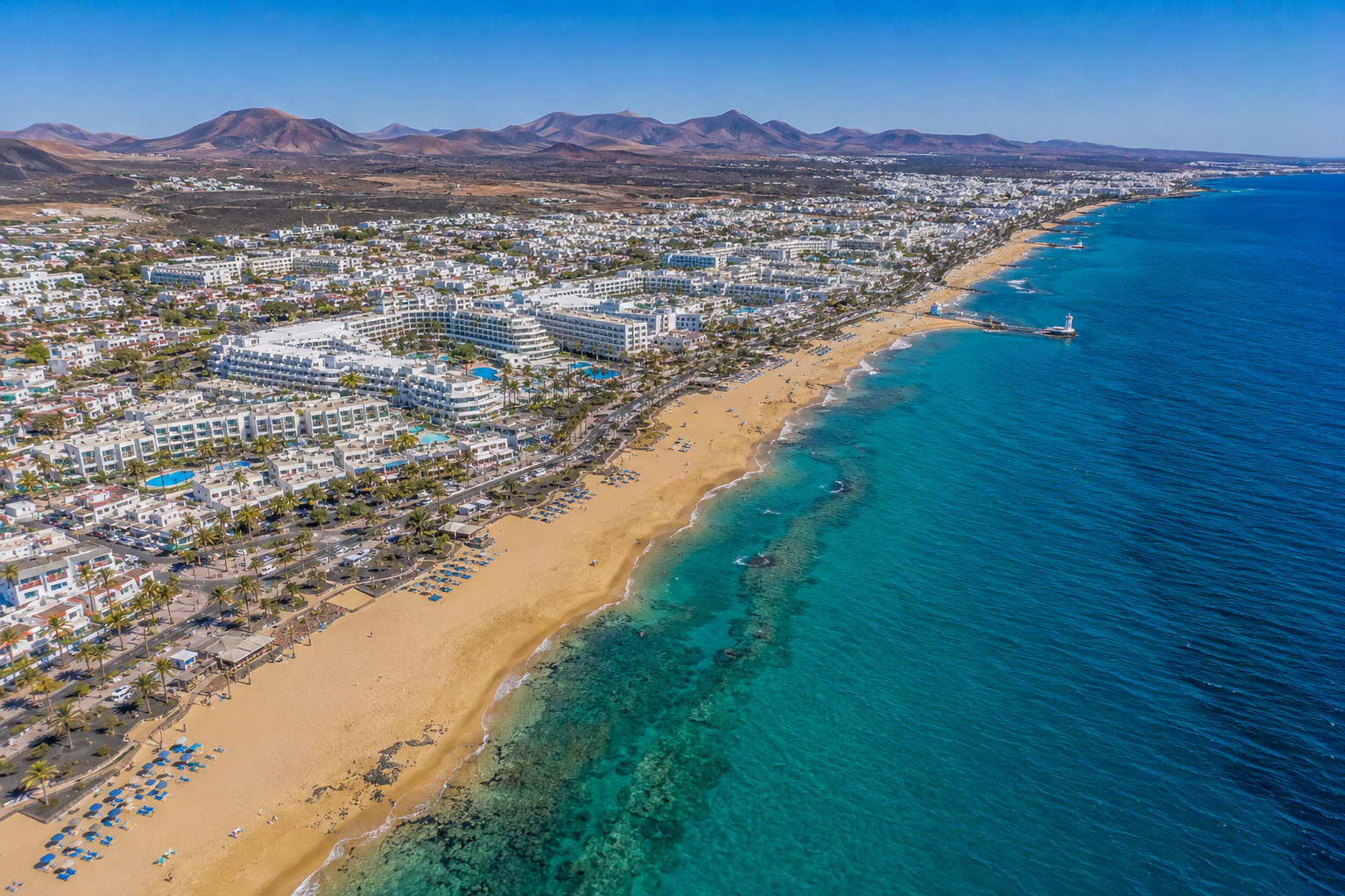 Puerto del Carmen på Lanzarote – helikoptervy över Kanarieöarnas största resort med 7 km strandremsa, vitkalkade hotell och Atlanten