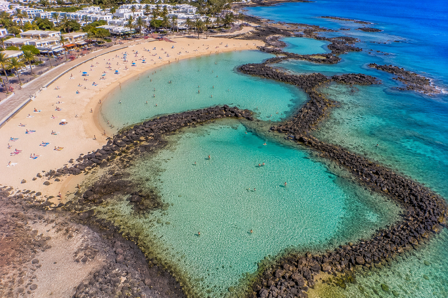 Puerto del Carmen på Lanzarote – helikoptervy över Kanarieöarnas största resort med 7 km strandremsa, vitkalkade hotell och Atlanten